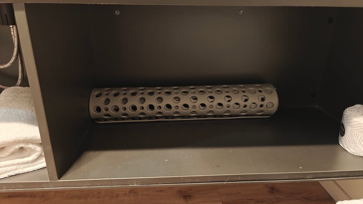A shelf with a rolled bath mat and