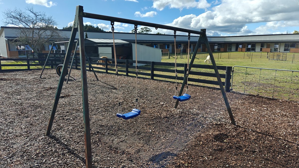 A swing set standing on bark chip with