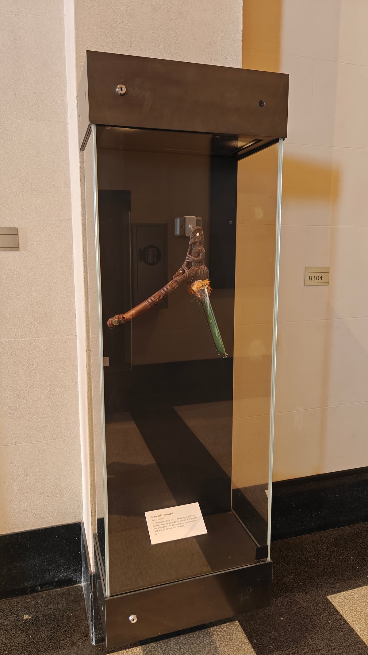 A tall case with a carved digging implement