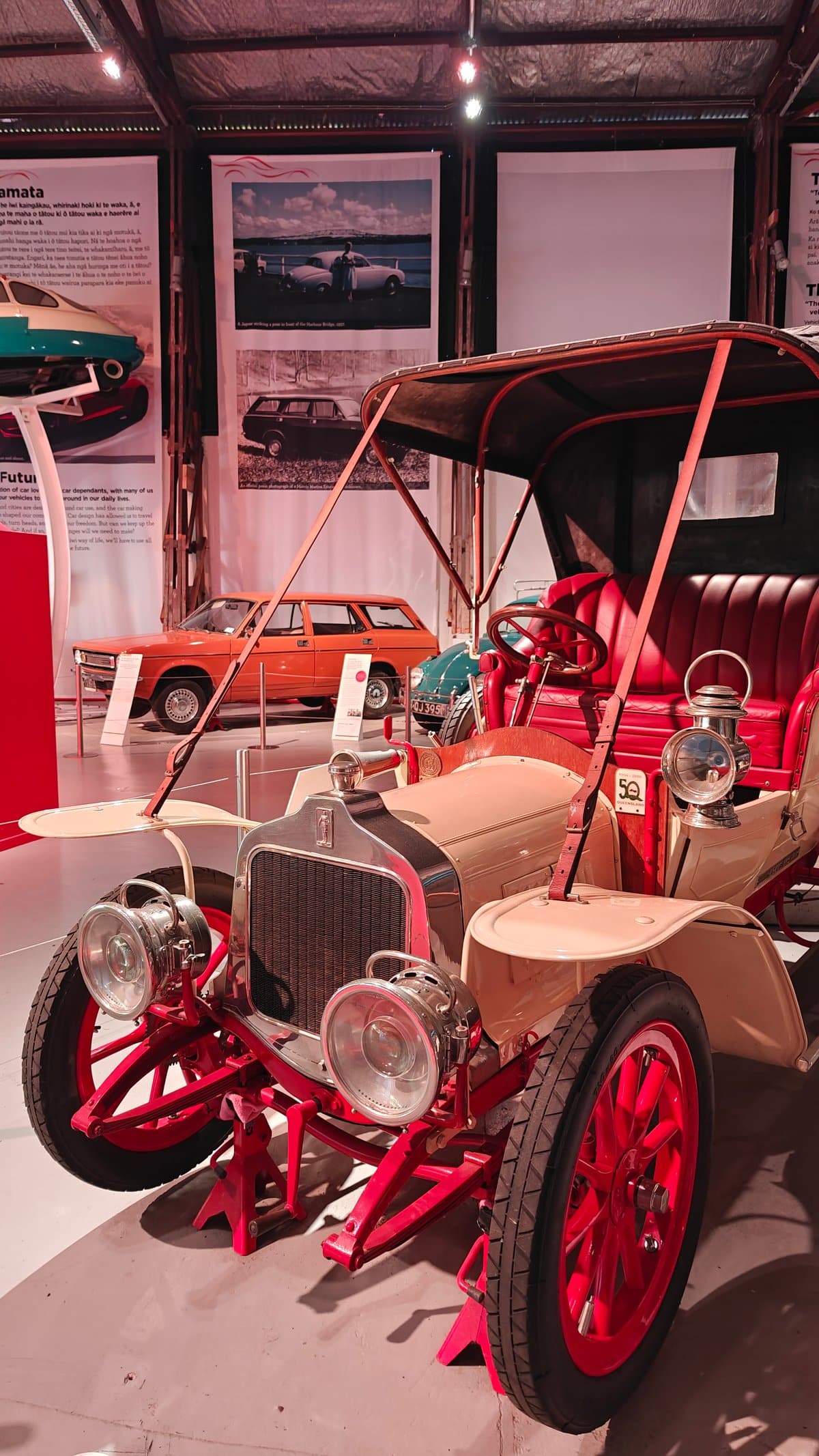 A vintage car chassis with red spoked wheels