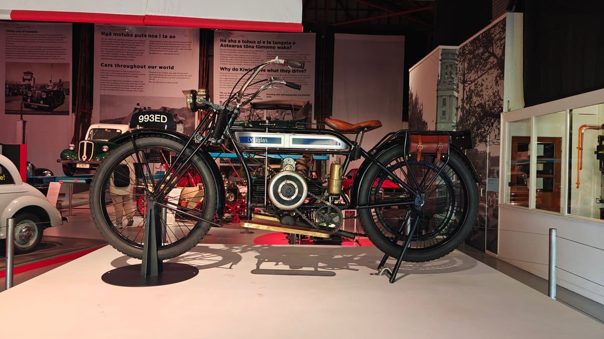 A vintage motorcycle displayed with bicycles ranged behind