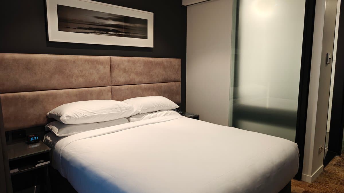 Bed with desk and chair beyond