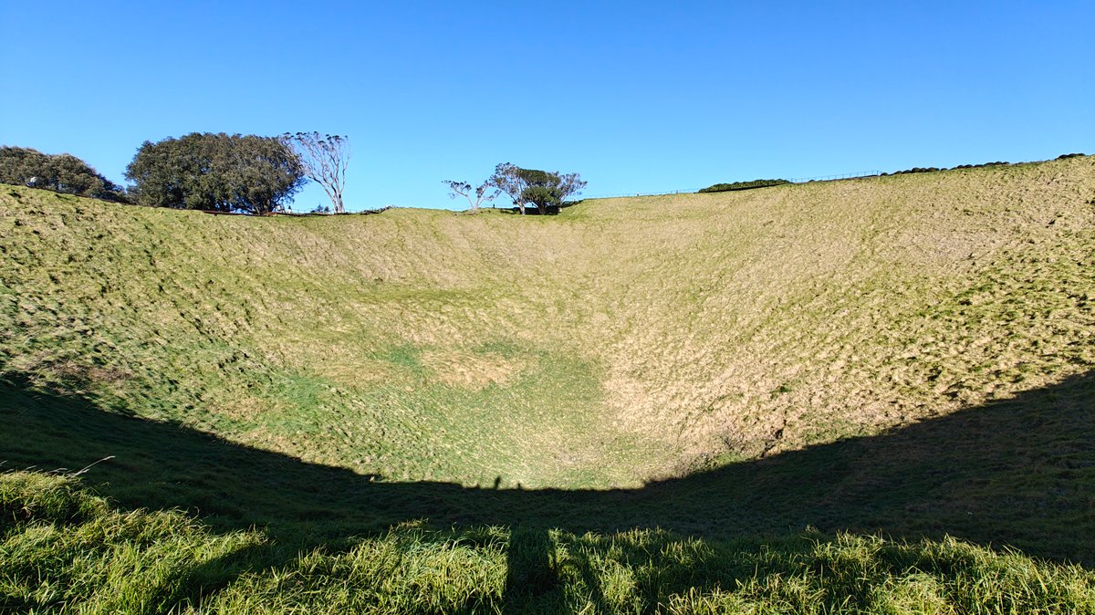 Grassed crater rim under blue sky