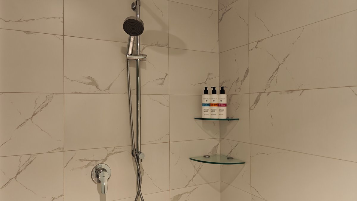 Marble-tiled shower with glass shelf