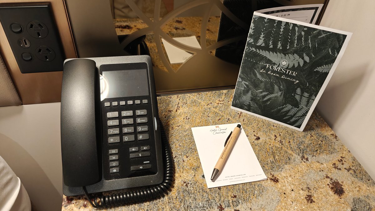 The bedside with the phone, a notepad, pen