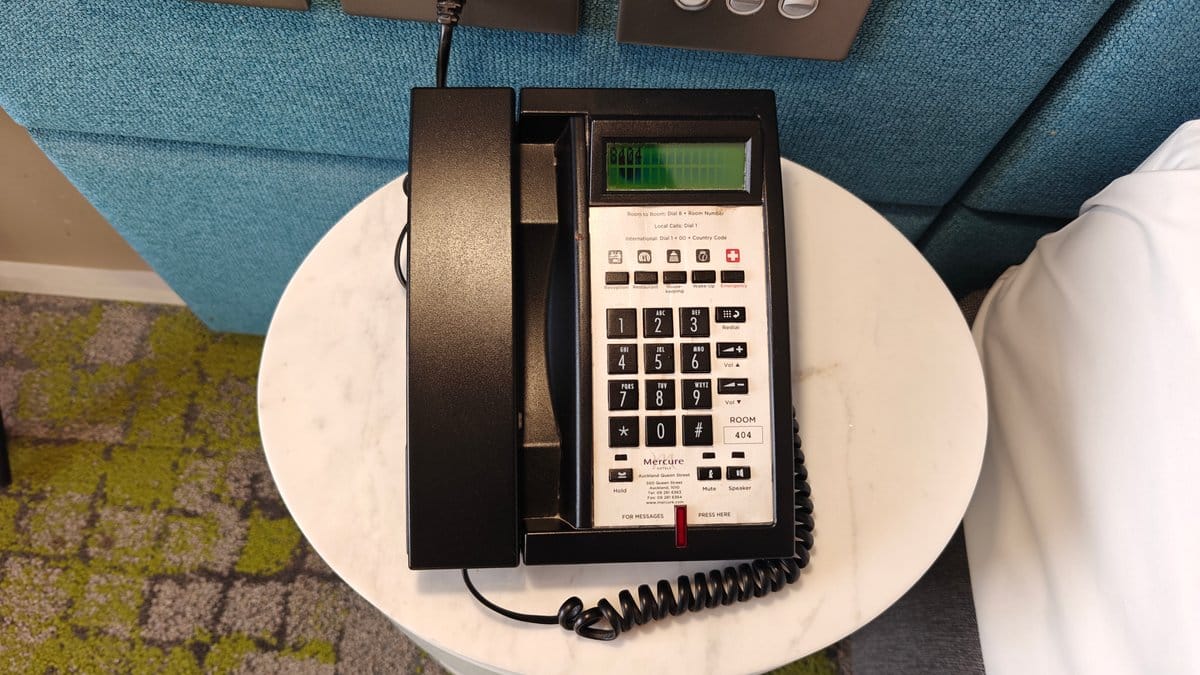 The telephone on the round bedside table.