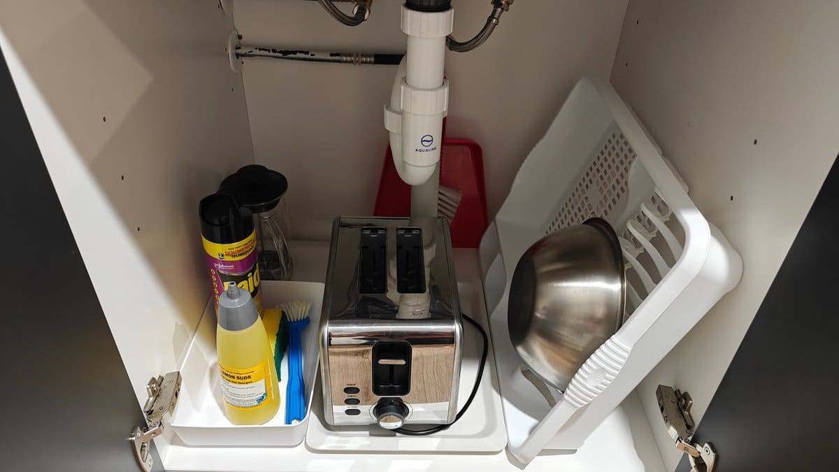 The under-sink cupboard with cleaning products, a toaster