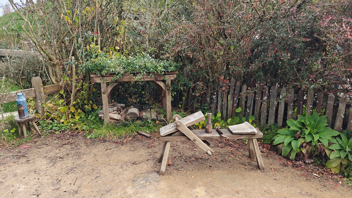 The workshop yard with sawhorses and cut timber.